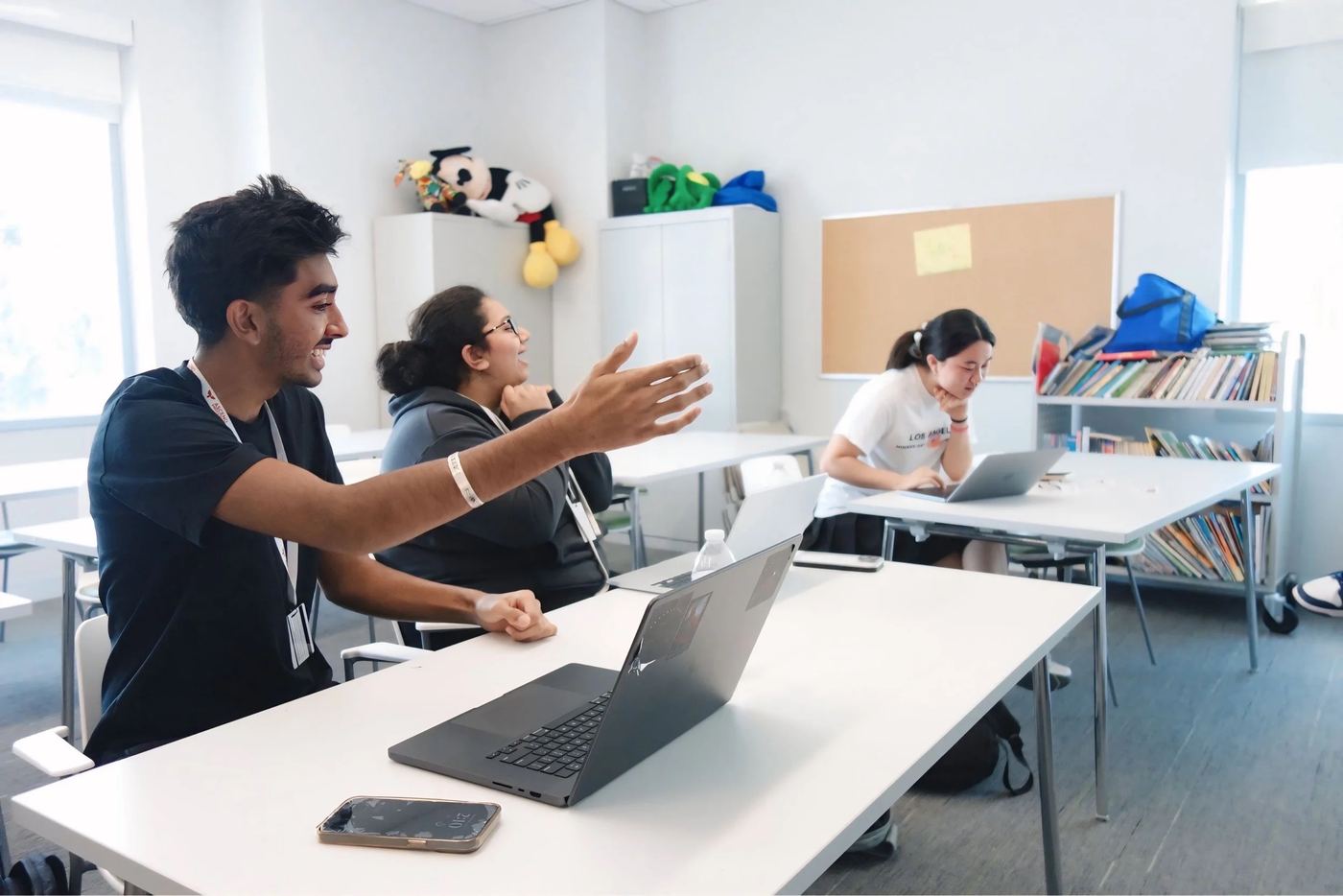 A student explaining an idea to classmates in a bright classroom