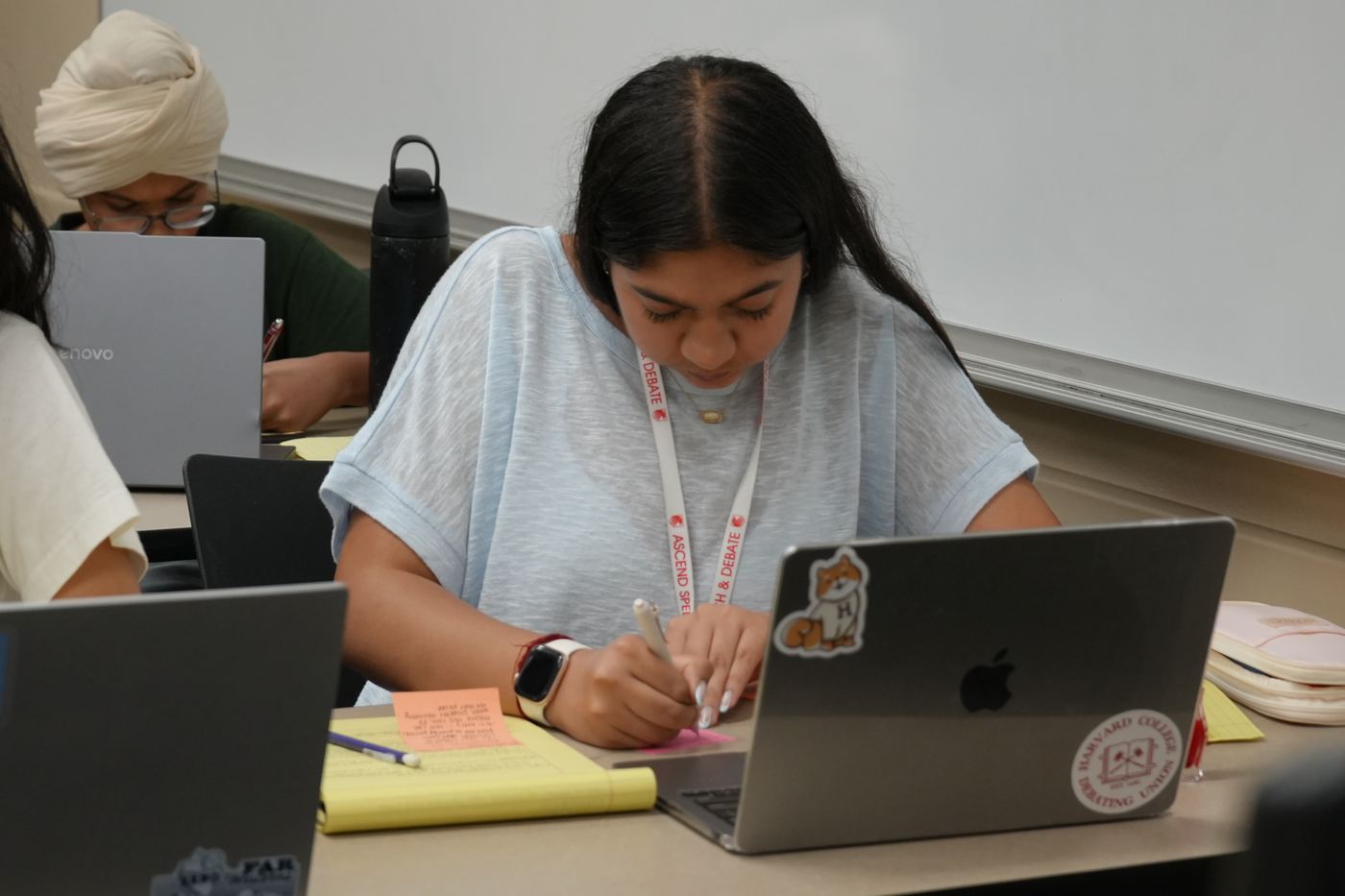 A student taking notes beside her laptop
